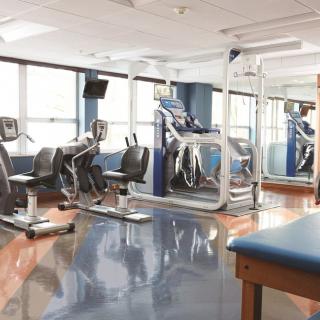 An empty gym equipped with treadmills and stationary bikes, ready for use.