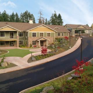 A large, well-landscaped residential building surrounded by trees.