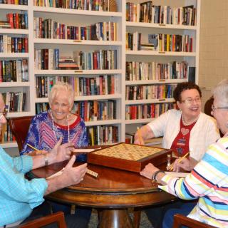 A group of elderly people enjoying a game together in a library setting.
