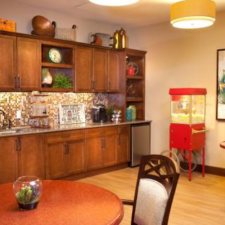 A cozy kitchen with wooden cabinets, a dining table, and a popcorn machine.