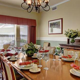An elegantly decorated dining room with a large table set for a meal, featuring a chandelier and floral arrangements.