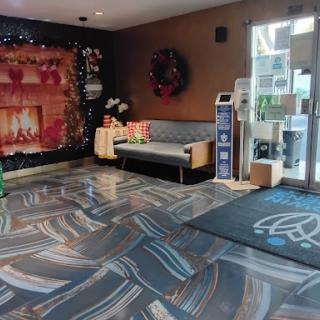 A cozy hotel lobby decorated for the holiday season, featuring a seating area and a festive fireplace backdrop.