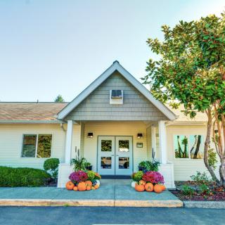 A welcoming building entrance adorned with colorful flowers and surrounded by greenery.