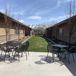 A courtyard with tables and chairs between two buildings under a clear sky.