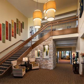 A modern lobby with a staircase and seating area, adorned with artwork and pendant lighting.