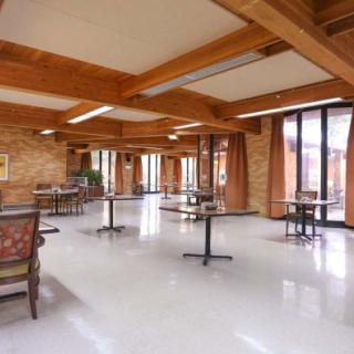 An empty dining area with wooden beams and large windows.