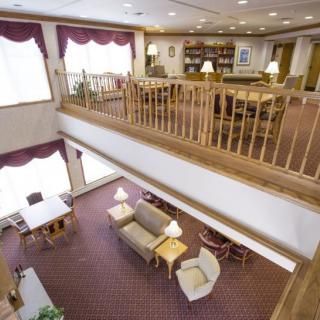 A cozy library interior with a reading area and bookshelves, featuring two levels and comfortable seating.