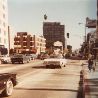 A vintage city street scene with classic cars and buildings.