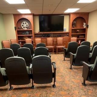 A small theater room with rows of seating facing a large screen.