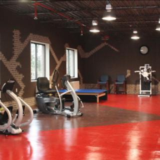 A modern gym space featuring various exercise machines and vibrant red flooring.