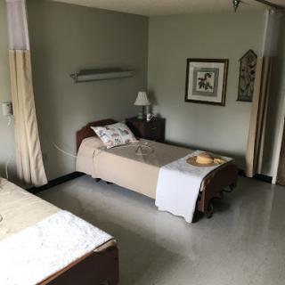A minimalist bedroom with two single beds, featuring a calming green wall and simple decor.