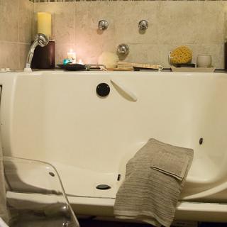 A cozy bathroom setup with a candlelit bathtub and a soft towel draped over the side.