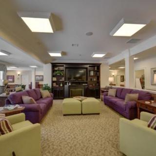 A spacious living room with colorful sofas and a central television setup.