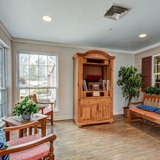 A cozy living room with a wooden cabinet, comfortable seating, and lush plants.