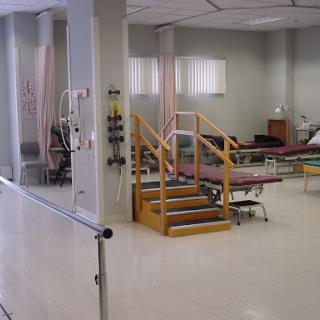 A view of a hospital rehabilitation area featuring beds and a staircase for patient mobility.