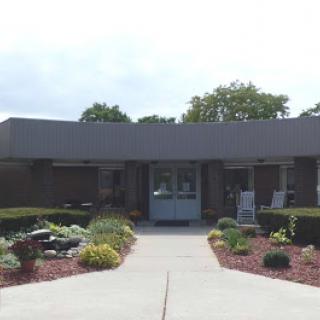 A welcoming entrance to a modern building surrounded by well-maintained gardens.