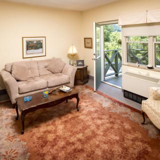 A cozy living room with a sofa, coffee table, and a view of the balcony.