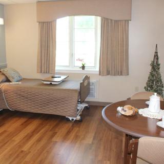 A cozy bedroom with a single bed, wooden flooring, and a small table beside the window.