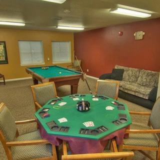 A cozy game room featuring a poker table set with cards and chips, alongside a pool table and comfortable seating.