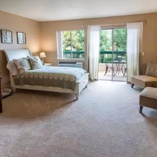 A cozy bedroom with a large bed, comfortable seating, and access to a balcony.