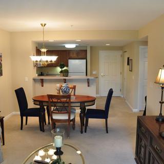 A cozy dining room with an open layout, featuring a wooden table, elegant chairs, and ambient lighting.