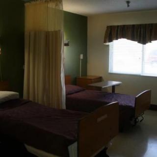 A hospital room with two beds and a dividing curtain.