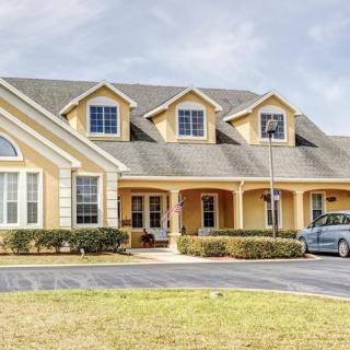 A large suburban house with a driveway and car parked in front.