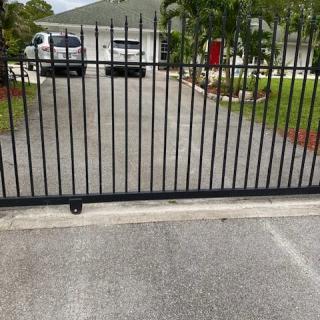 A driveway with a closed metal gate and parked cars.