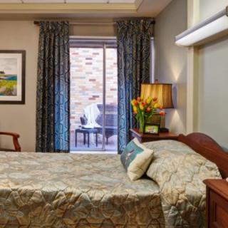 A cozy bedroom interior with a neatly made bed, elegant curtains, and a bedside lamp.