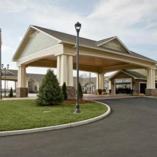 A building entrance with a covered driveway and landscaped area.