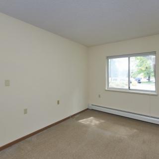 An empty room with carpet flooring and a window letting in natural light.