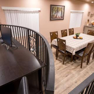 A cozy dining area featuring a wooden table set for meals, surrounded by elegant chairs and warm lighting.