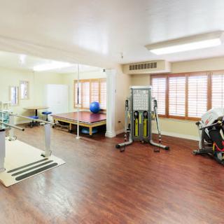 A spacious gym area equipped with various exercise machines in a bright, inviting setting.
