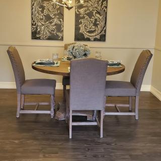 A cozy dining room with a round table and four upholstered chairs, adorned with wall art.