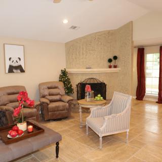 A cozy living room with armchairs, a coffee table, and a fireplace, featuring elegant decor and artwork.