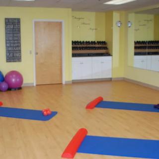 An empty yoga studio with exercise mats, fitness balls, and a large mirror.