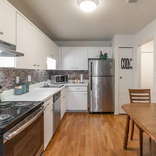A modern kitchen with stainless steel appliances and wood flooring.