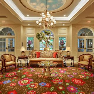 A luxurious lobby featuring a chandelier, elegant furniture, and a colorful carpet.