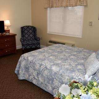 A cozy bedroom featuring a patterned bedspread, comfortable seating, and soft lighting.