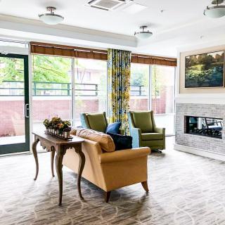 A modern living room with stylish seating, a decorative fireplace, and large windows allowing natural light to flood the space.
