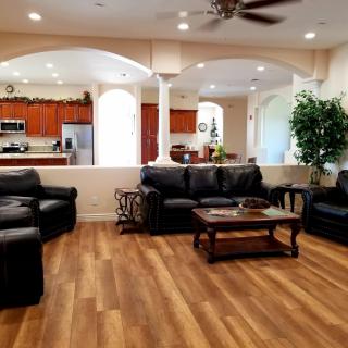 Spacious open-concept living room with leather sofas and a view of the kitchen.