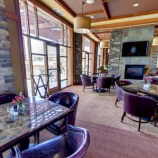 A modern dining area with purple chairs, tables, and a cozy fireplace.