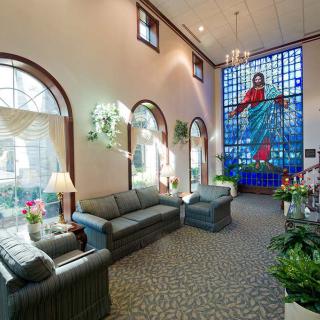 A well-lit lobby with comfortable seating and a prominent stained glass window depicting a religious scene.