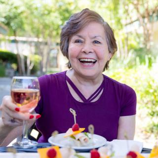 A woman enjoying a meal outdoors with a glass of wine.