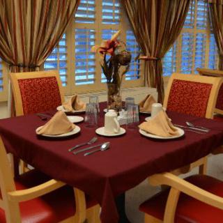 A beautifully set dining table with elegant tableware and a decorative centerpiece, surrounded by stylish curtains.