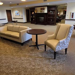 A cozy lobby area with a sofa, armchair, and table on a carpeted floor.