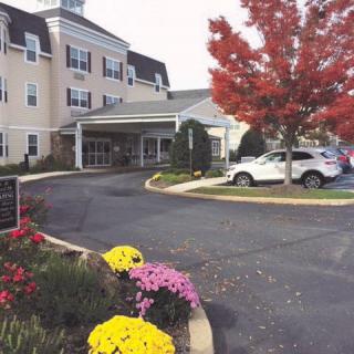 A building entrance surrounded by autumn foliage and colorful flowers.