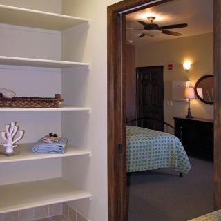 A cozy bedroom with a view of decorative shelves and a bed with a checkered duvet.