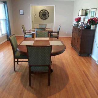 A neatly arranged dining room with a wooden table and chairs on a hardwood floor.