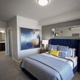 A modern bedroom featuring a large artwork above the bed, with stylish bedding and decor.